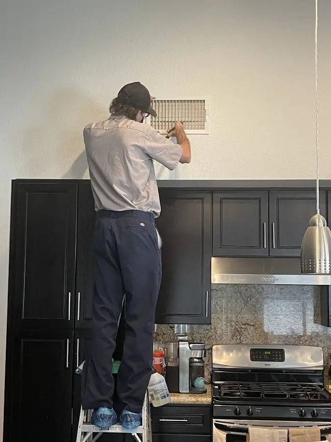 Technician inspecting an air vent during HVAC service in Andover